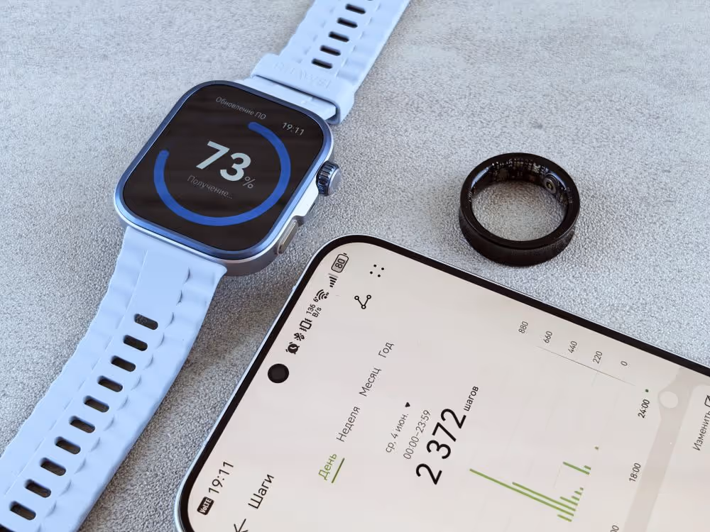 Smartwatch, anel inteligente e smartphone com dados de saúde dispostos sobre superfície cinza