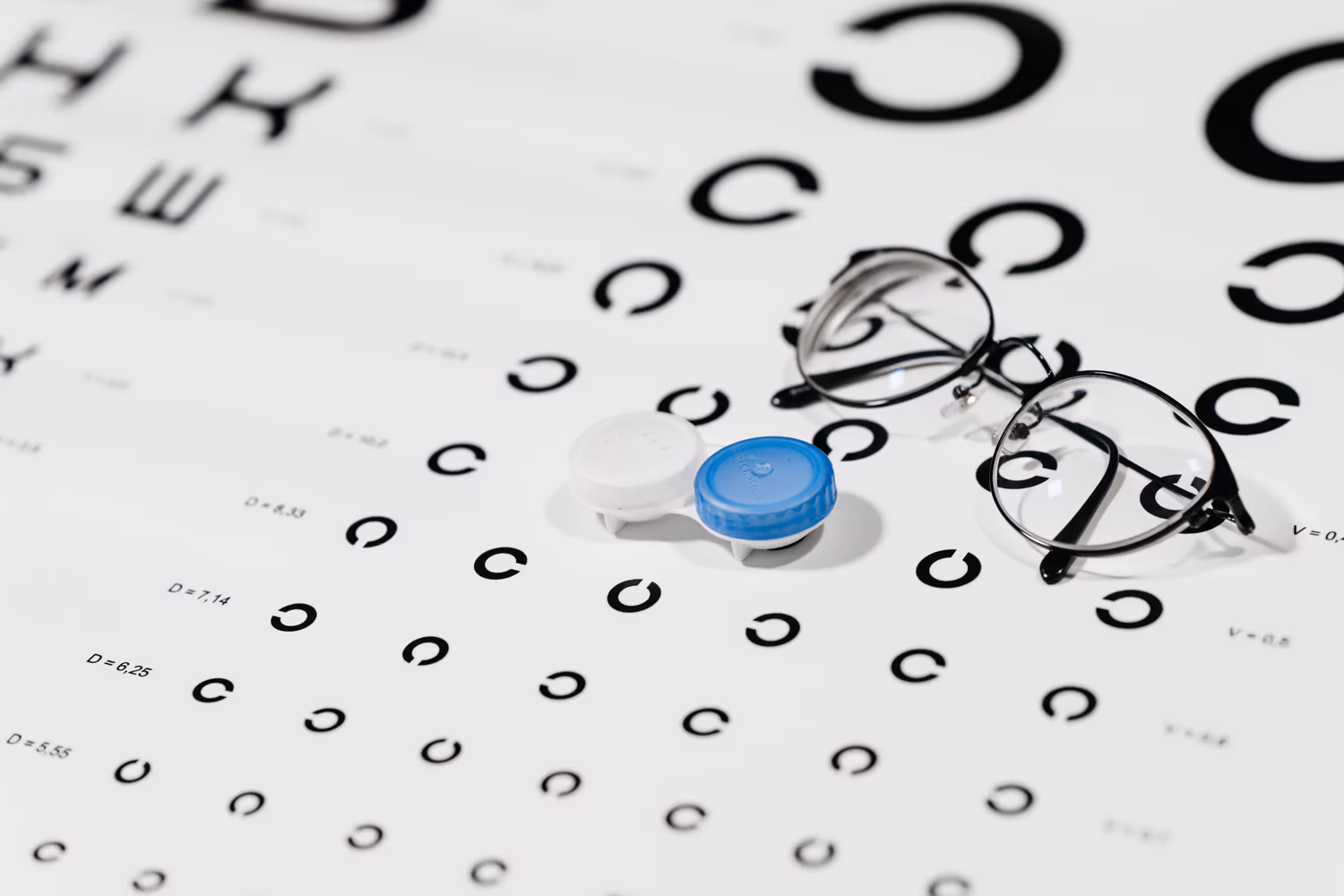 Estojo de lentes de contato e óculos sobre uma tabela de visão Estojo de lentes de contato e óculos sobre uma tabela de visão