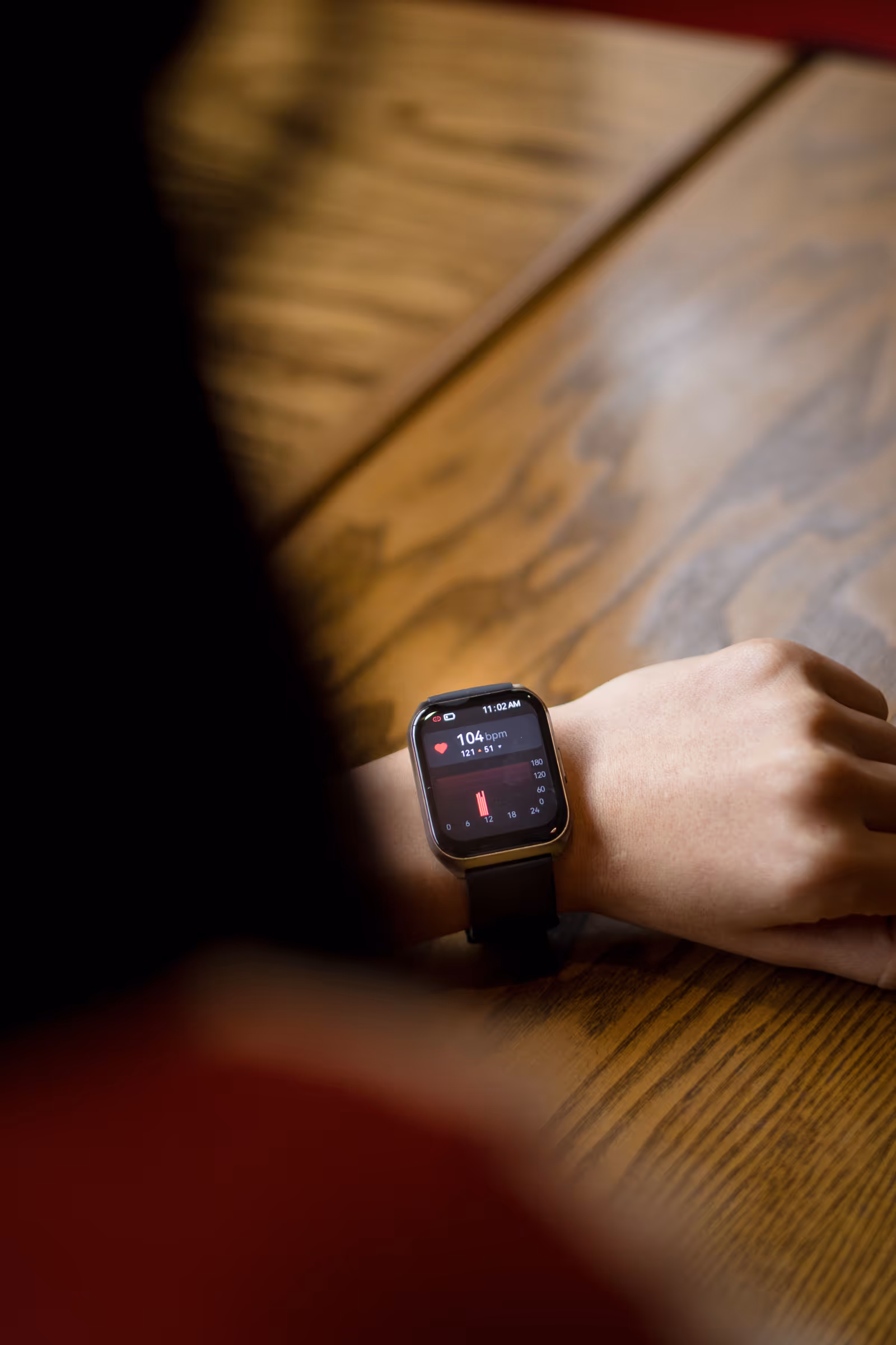Pessoa olhando para o smartwatch no pulso exibindo frequência cardíaca de 104 bpm Pessoa olhando para o smartwatch no pulso exibindo frequência cardíaca de 104 bpm