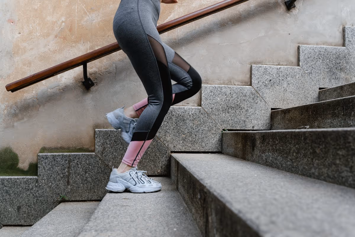 Mulher com roupa esportiva subindo escada de concreto ao ar livre Mulher com roupa esportiva subindo escada de concreto ao ar livre