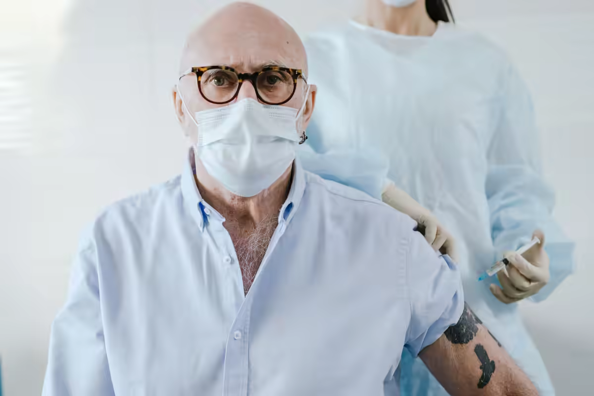 Homem idoso recebe uma vacina no braço em consultório
